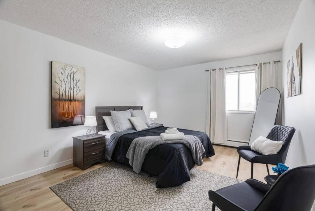 ein Schlafzimmer mit einem Bett und einem Stuhl darin in der Unterkunft 1BR with Balcony Newly Renovated Downtown in Fort McMurray