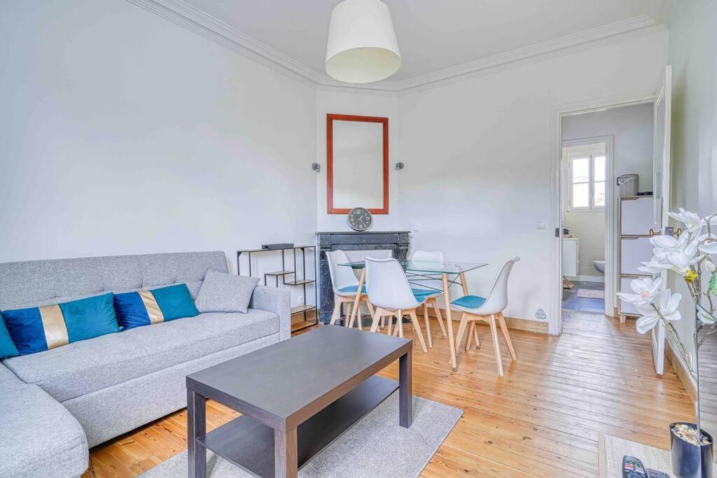 een woonkamer met een bank en een tafel bij Appartement dans résidence calme, proche de Paris in La Garenne-Colombes