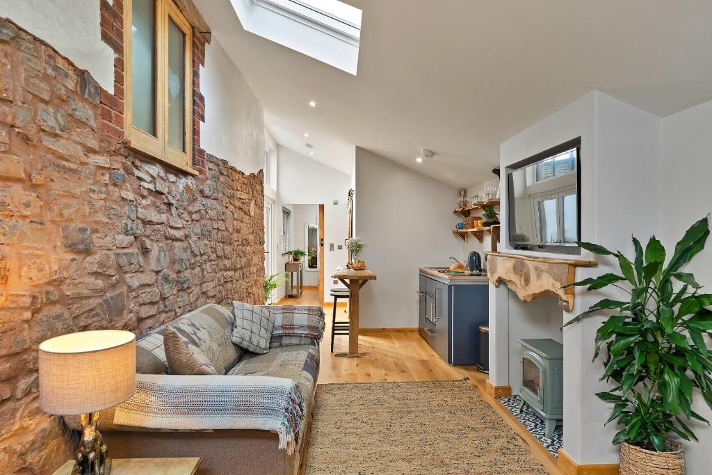 a living room with a couch and a stone wall at Finest Retreats - Hillfarrow Hideaway in Tiverton
