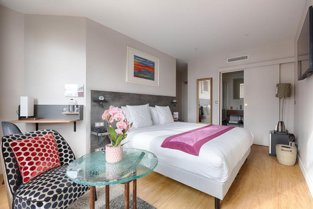 ein Hotelzimmer mit einem Bett und einem Glastisch in der Unterkunft Hotel de France Invalides in Paris