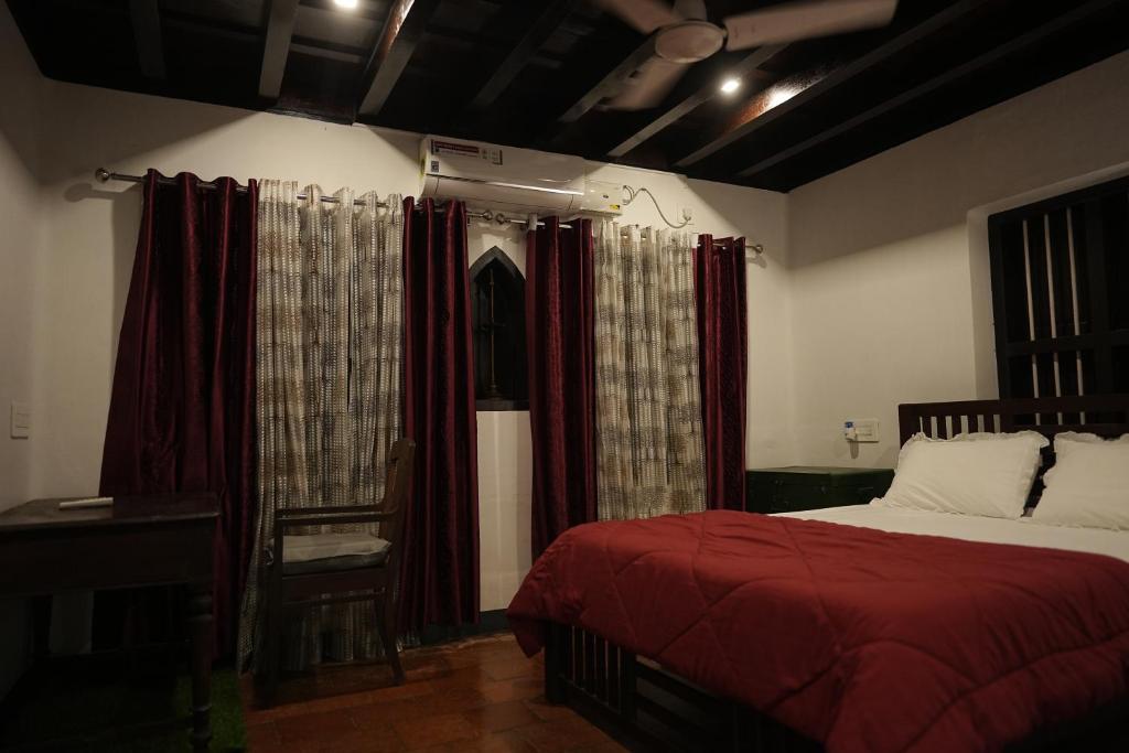 Schlafzimmer mit einem Bett mit roter Bettwäsche und Vorhängen in der Unterkunft Kayyalas Courtyard in Thrissur