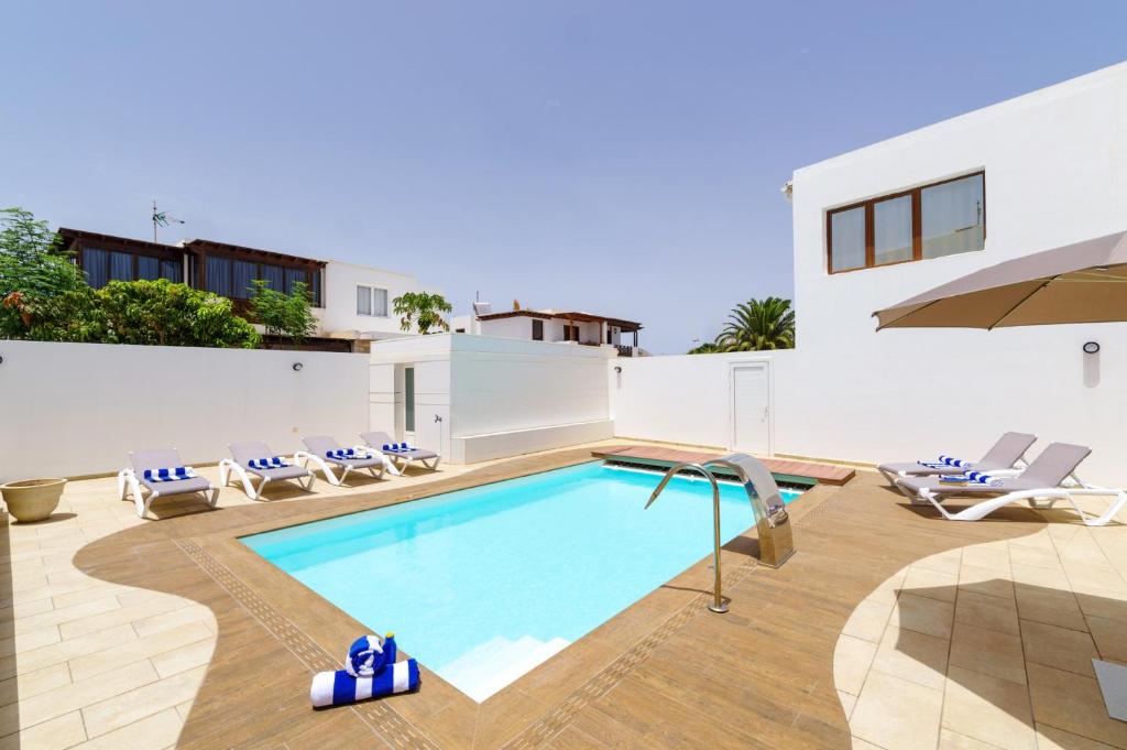 a villa with a swimming pool and lounge chairs at Villa Tisalaya by Villa Plus in Puerto del Carmen