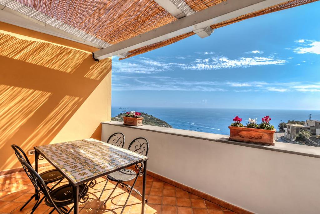 a balcony with a table and chairs and the ocean at Villarena Relais in Nerano