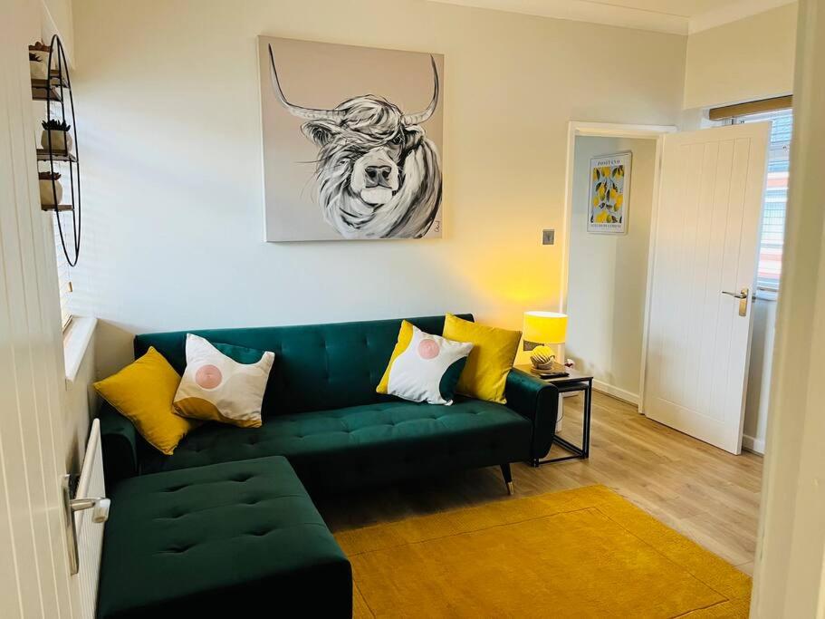 a living room with a green couch and a bull painting at Stylish Central Apartment in Cardiff