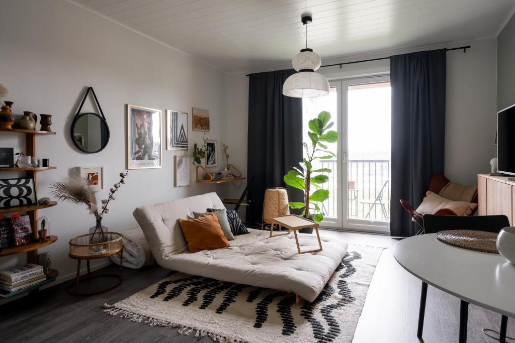uma sala de estar com um sofá branco e uma mesa em Viihtyisä yksiö, oma parkkipaikka, wifi, Aino Areena 300m em Järvenpää