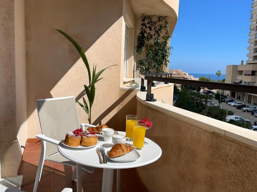 贝纳尔马德纳Luxury apartment Benalmadena First line的阳台上的一张桌子上备有松饼和饮料