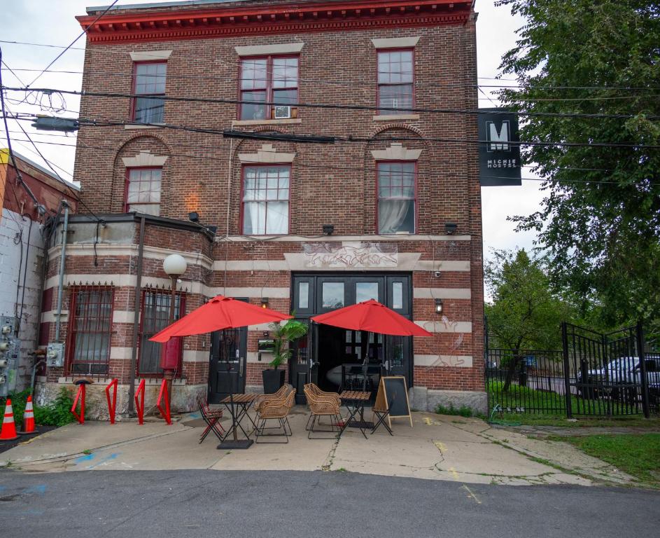 un edificio con sillas y sombrillas rojas delante de él en Michie Hostel, en Providence