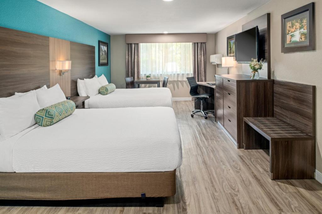 Una habitación de hotel con dos camas y un escritorio. en Yosemite Southgate Hotel &amp; Suites, en Oakhurst