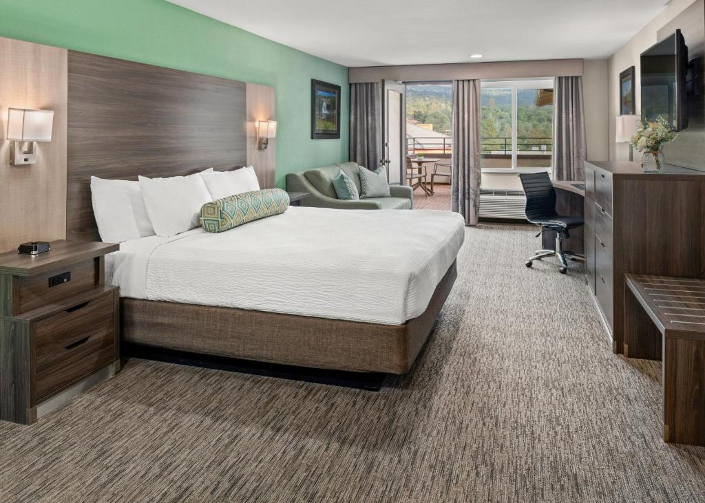 a hotel room with a large bed and a desk at Yosemite Southgate Hotel & Suites in Oakhurst