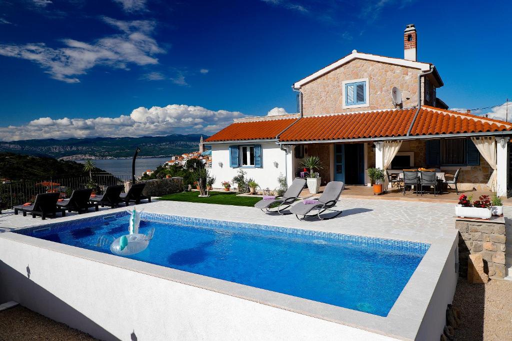 a villa with a swimming pool in front of a house at Romantic stone villa with pool, panoramic sea view near the beach - by Traveler tourist agency Krk ID 2134 in Vrbnik