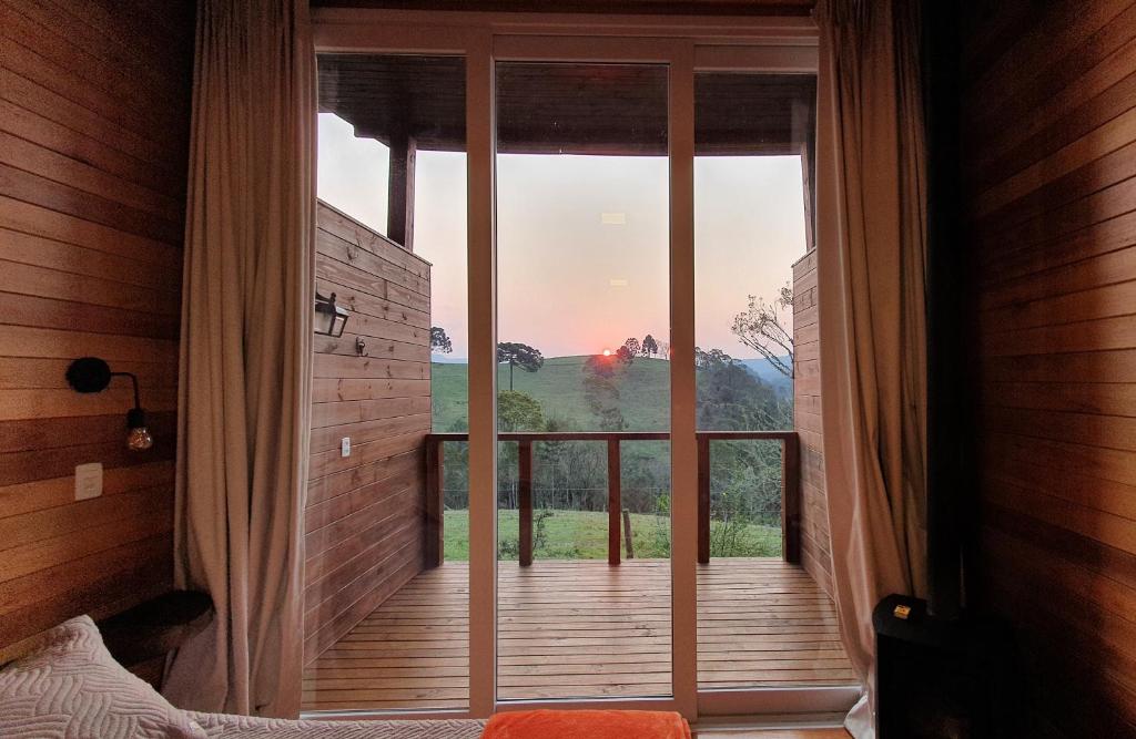 Zimmer mit einer großen Glastür zu einem Balkon in der Unterkunft Pousada Bracatinga in Bom Retiro