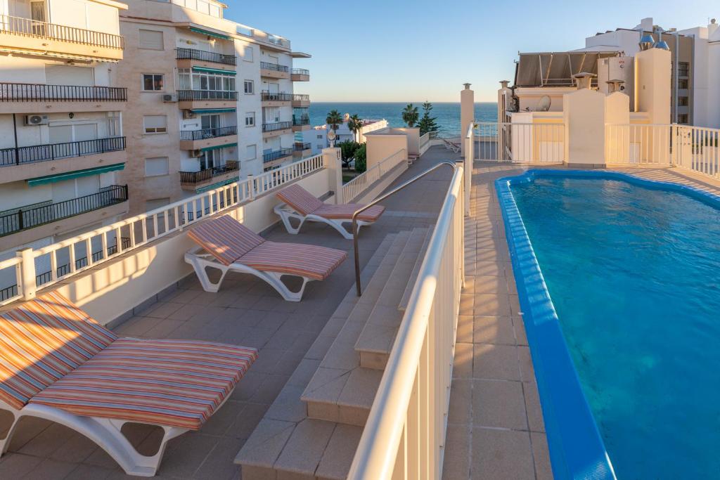 a balcony with two chairs and a swimming pool at Apartamentos Solset Nerja in Nerja