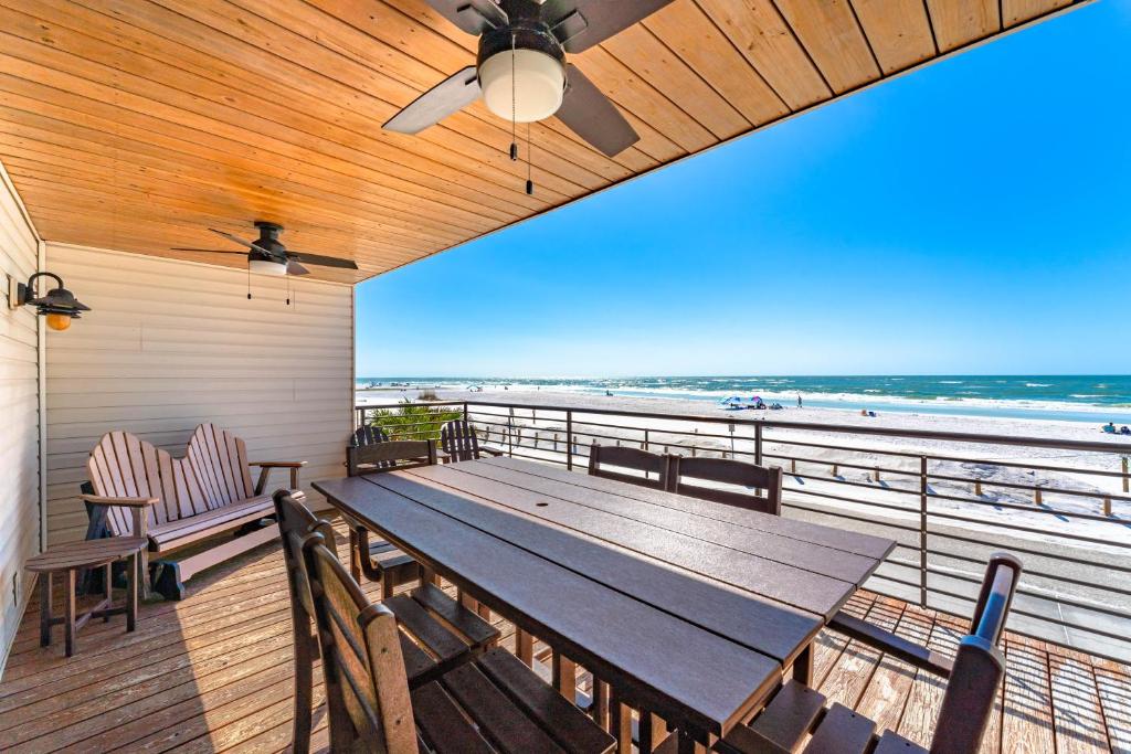 eine Terrasse mit einem Holztisch und Stühlen sowie Strand in der Unterkunft Fanta-Sea 55 in Siesta Key