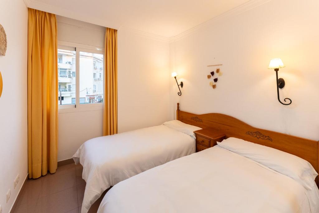 two beds in a room with a window at Apartamentos Solset Nerja in Nerja