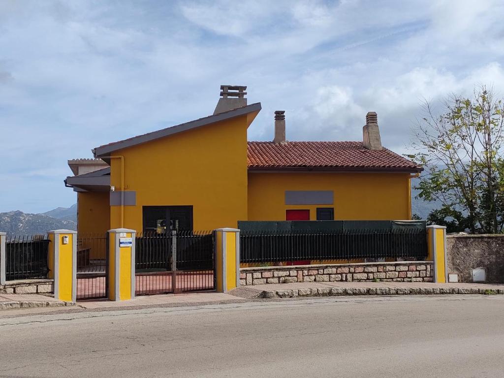 uma casa amarela com uma cerca em frente em Tempio Pausania Solar private apartment 30 minutes from the sea - Appartamento solare a 30 minuti dal mare em Tempio Pausania