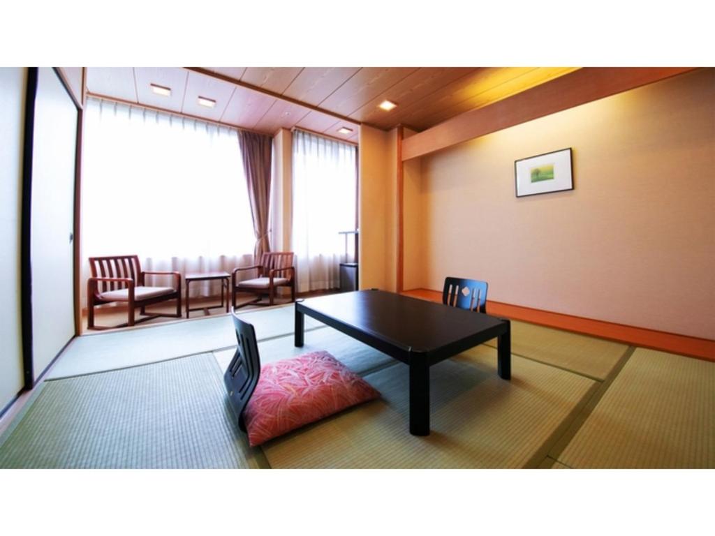 Kesennuma Plaza Hotel - Vacation STAY 15381v في Kesennuma: غرفة بطاولة وكراسي وطاولة وكراسي