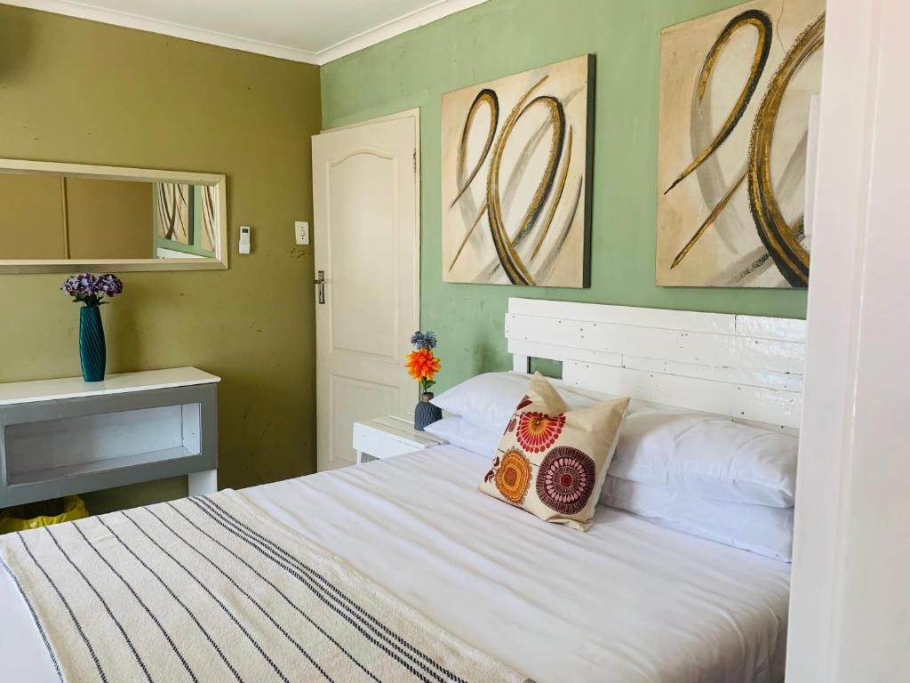a bedroom with a bed and two paintings on the wall at SURVIVOR GUEST HOUSE-Giyani in Giyani