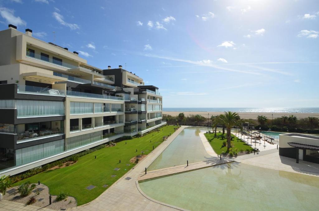 an apartment building with a swimming pool and a beach at Ocean Home EXCELLENT & SOLMARES in Isla Canela