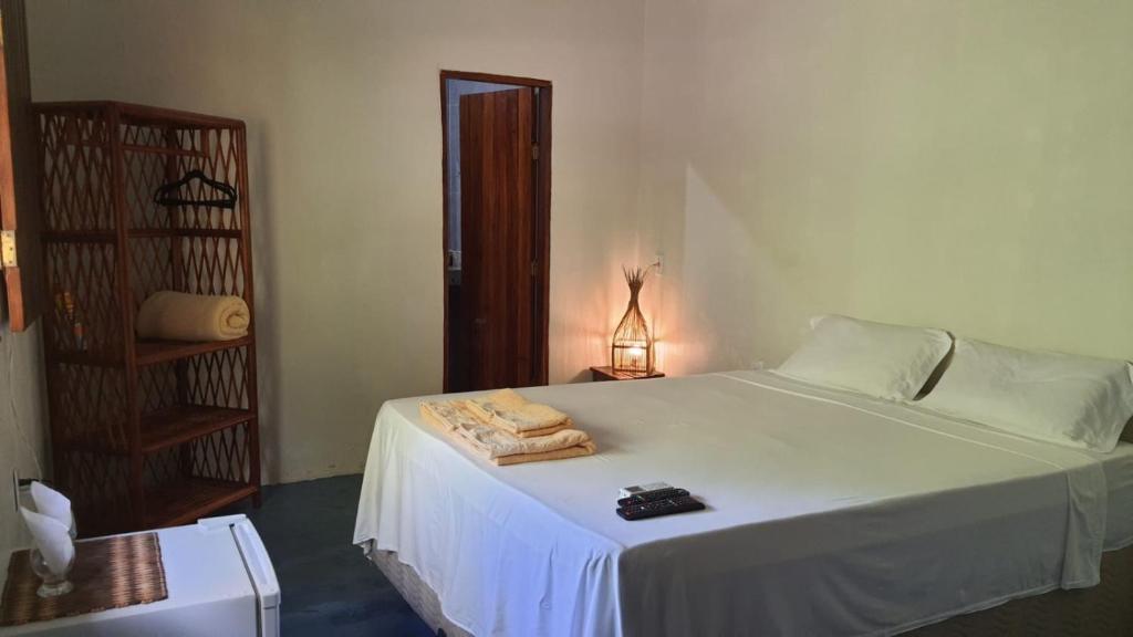 Un dormitorio con una cama blanca con toallas. en Casa Antiga Hospedagem en Barra Grande