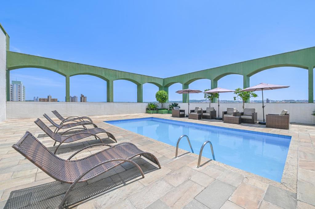 a pool with chairs and umbrellas on a building at Hotel Nacional Inn Limeira in Limeira