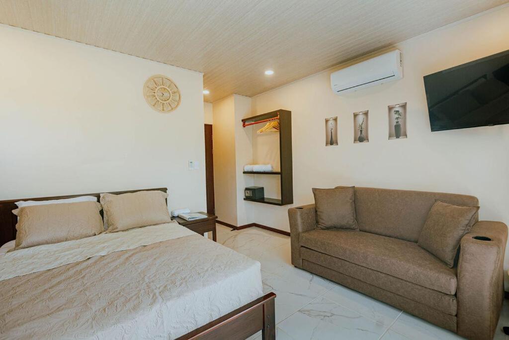a bedroom with a bed and a couch and a television at Mountain Top Park Hotel in Quepos