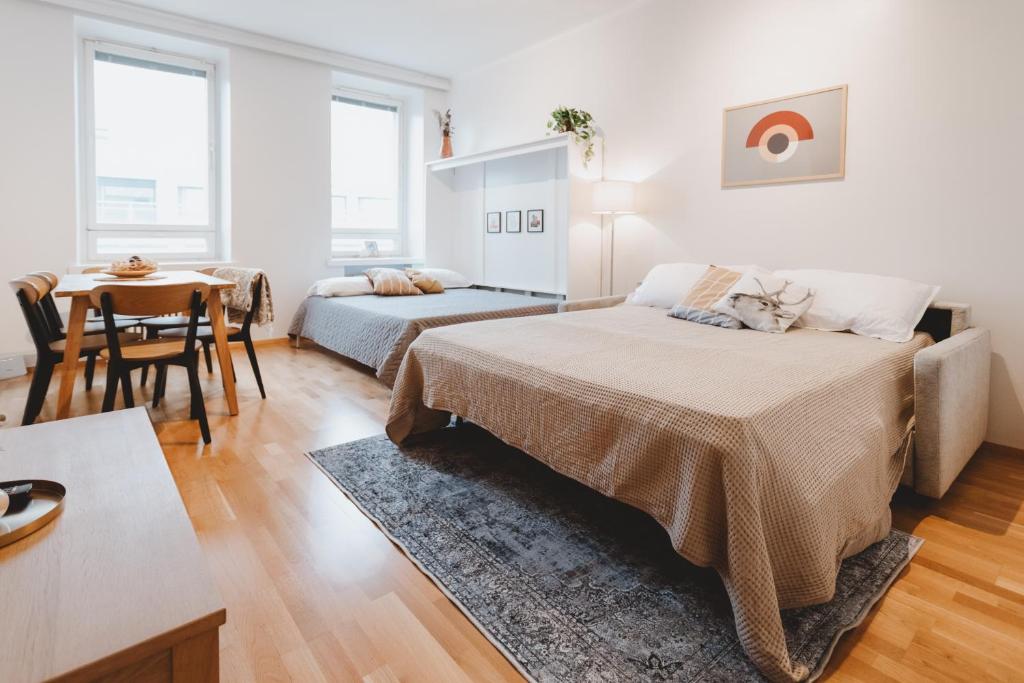 a bedroom with two beds and a table and a dining room at Scandic Primo Apartments - Malminkatu 49m2 in Helsinki