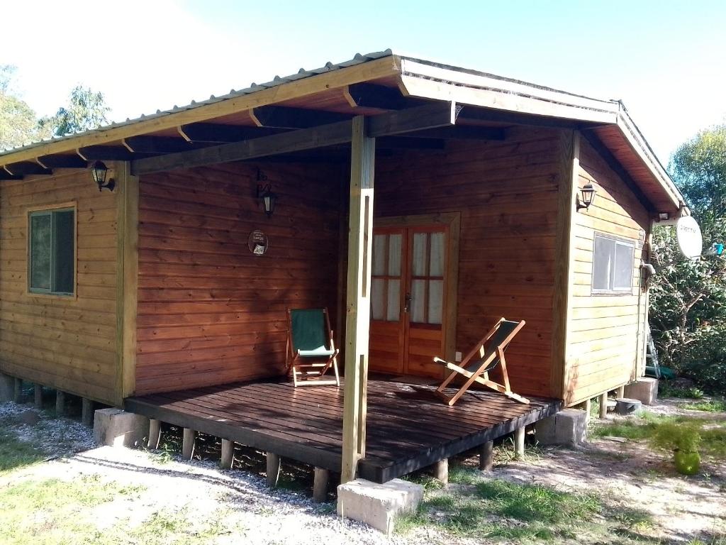 Cabaña de madera con terraza y silla en La Cabaña, en Sauce de Portezuelo