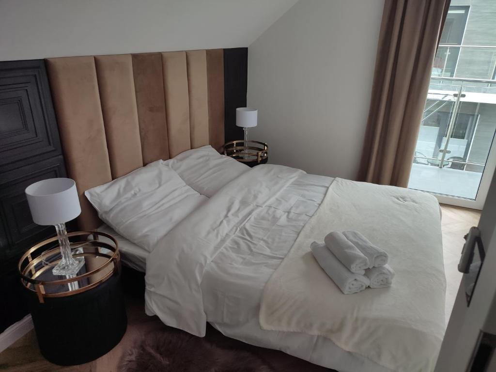 Una cama con sábanas blancas y dos toallas. en Golden Cliff HorizonPark Dziwnòwek, en Dziwnówek