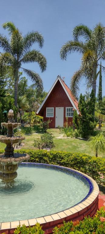 une fontaine en face d'une maison avec des palmiers dans l'établissement RESORT CHALÉ DA PRATA, à Curvelo