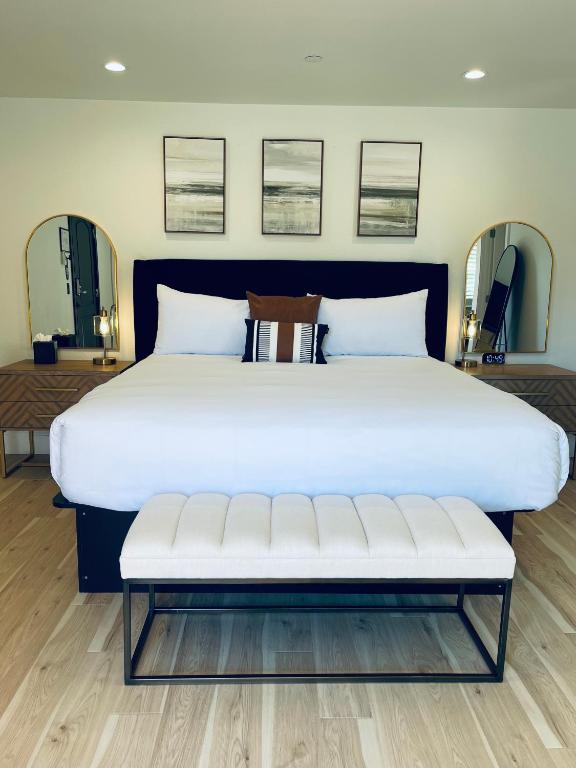 a large white bed with a bench in a room at New Haven Inn in Solvang