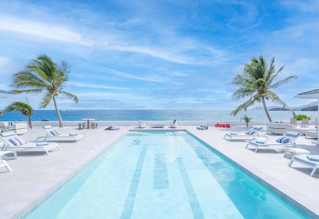 una piscina con tumbonas y el océano en 5 BR Luxurious Beachfront Villa with utmost privacy, en Les Terres Basses