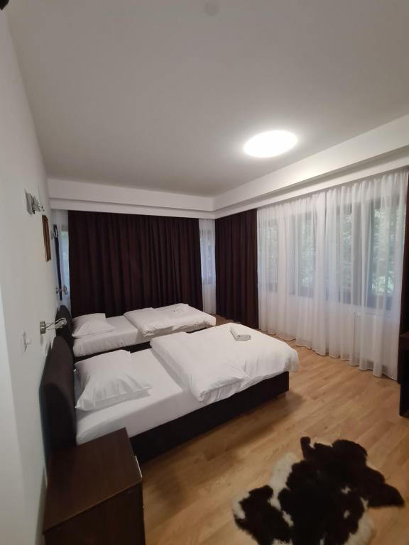 a bedroom with a bed with white sheets and curtains at Holiday Resort Zlatni Dol Mostar in Goranci