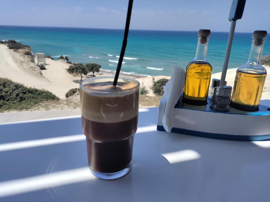 uma bebida numa mesa com vista para a praia em Mavros Gatos Apartments em Epanomi