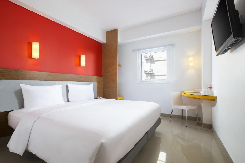 - une chambre avec un lit blanc et un mur rouge dans l'établissement Amaris Hotel Hertasning, à Makassar