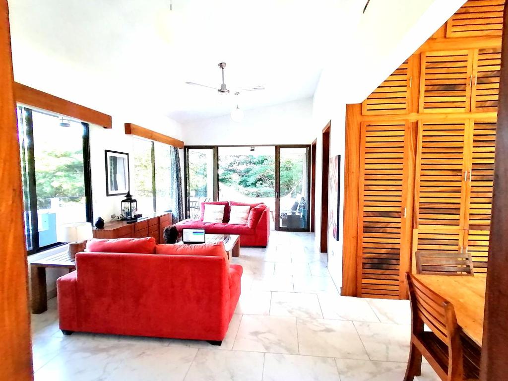 ein Wohnzimmer mit zwei roten Sofas und Fenstern in der Unterkunft Ananda Guesthouse in Balgue
