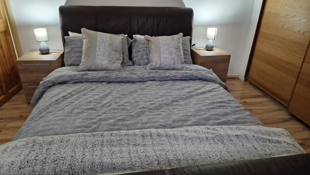 a bedroom with a large bed with two lamps at Comfortable 2 bedroom house with free parking and great transport links in Dagenham