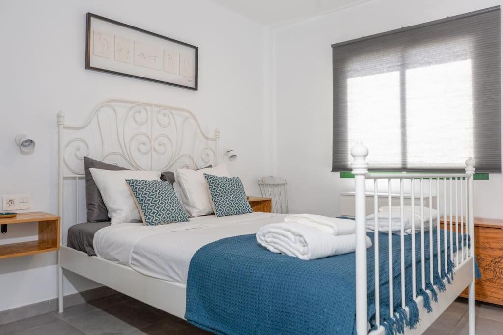 een slaapkamer met een wit bed en een blauwe deken bij Casa Turquesa, shared pool in Puerto del Carmen