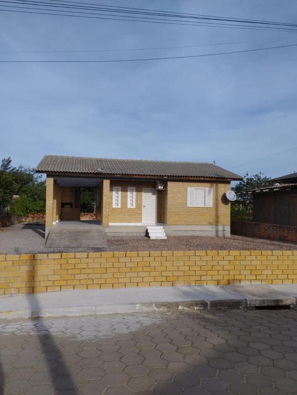 a house with a yellow brick retaining wall at CASA DE PRAIA ILHA in Araranguá