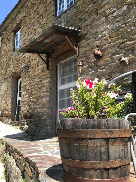 an old barrel with flowers in front of a stone building at Casa do Freire - Serra da Estrela in Aguincho