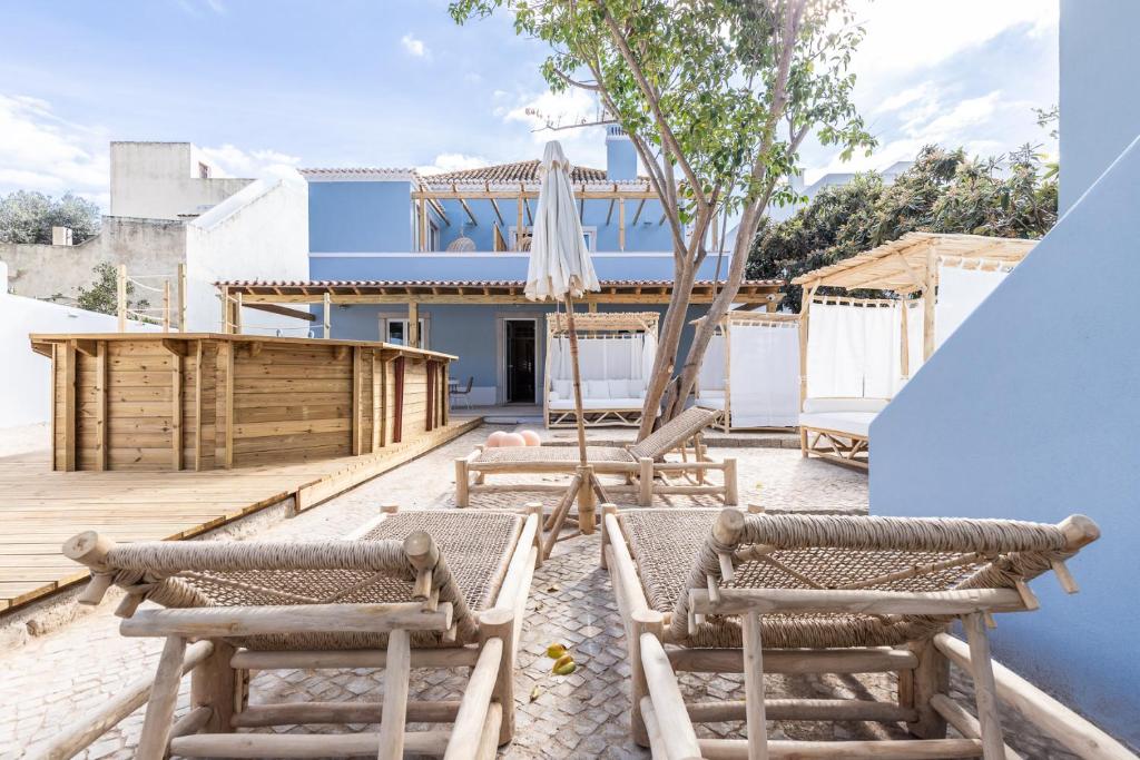 una casa con un patio con sillas y sombrillas. en Amália Boutique Suites & Studios - by @ rita´s place en Faro