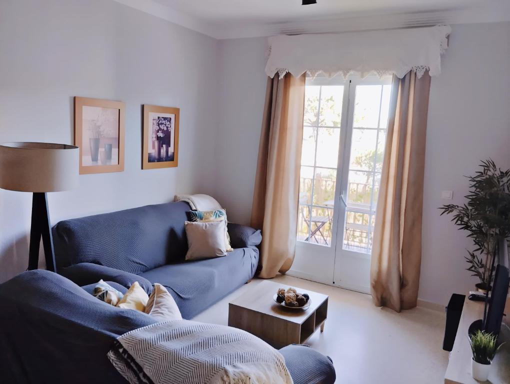 een woonkamer met een blauwe bank en een raam bij Apartamento de 3 habitaciones, zona muy tranquila a unos minutos de la playa in Mazagón