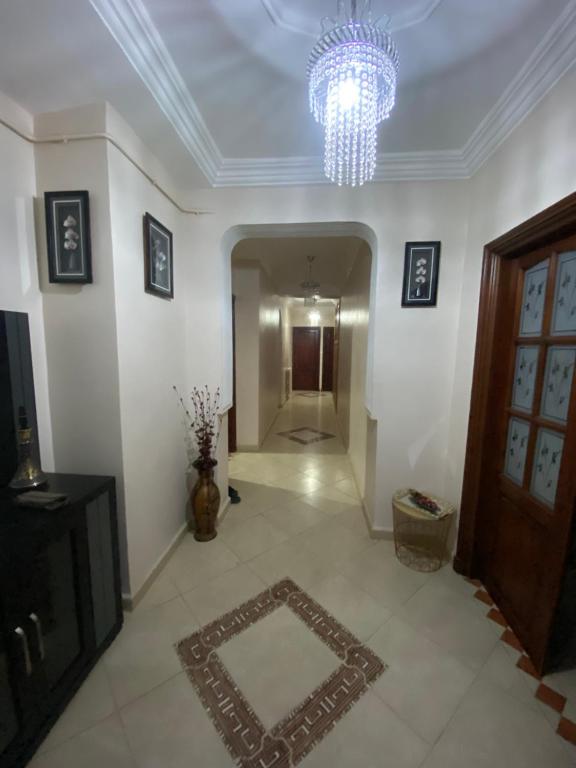 a living room with a chandelier and a hallway at Appartement haut standing in Tlemcen