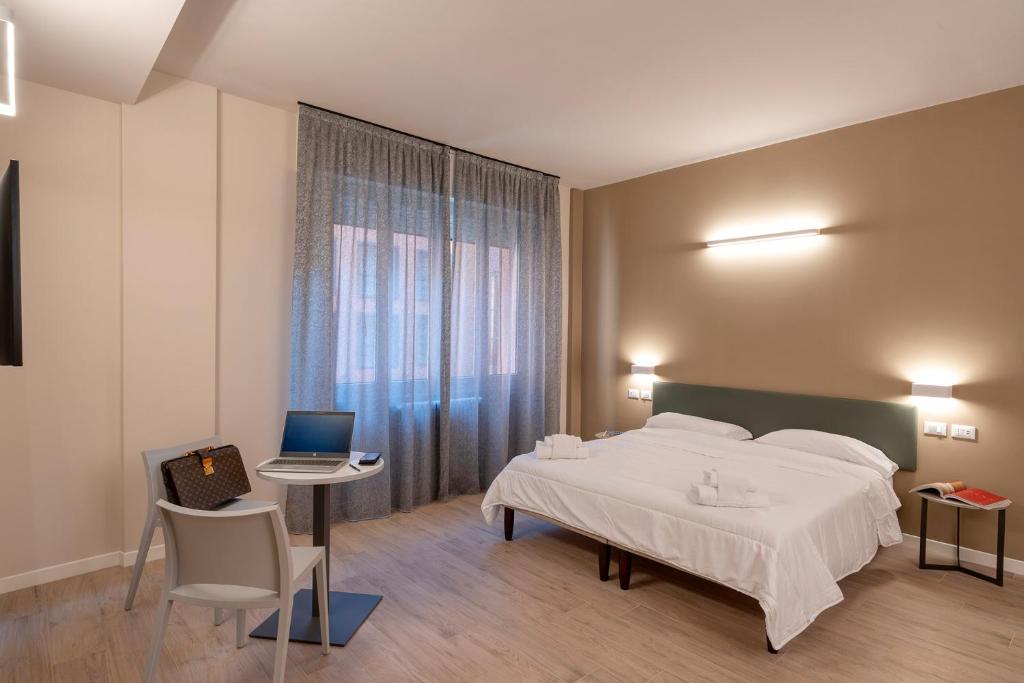 a bedroom with a bed and a table and a laptop at Astoria Comfort Rooms in Bologna