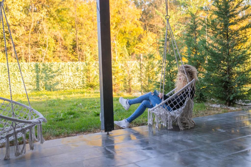 a girl sitting on a swing in a park at Dekan Forest Apartments Timisoara in Dumbrăviţa