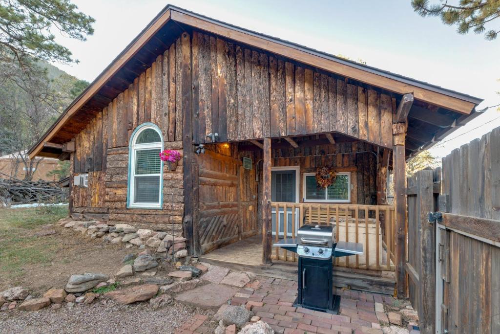 a log cabin with a grill in front of it at Rustic Log Cabin with Studio about 5 Mi to Pikes Peak! in Green Mountain Falls