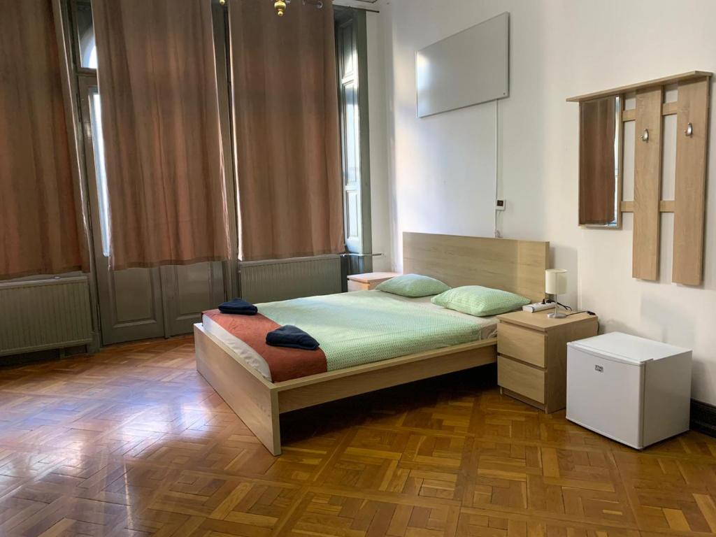 um quarto com uma cama e piso em madeira em Kecskeméti Rooms em Budapeste