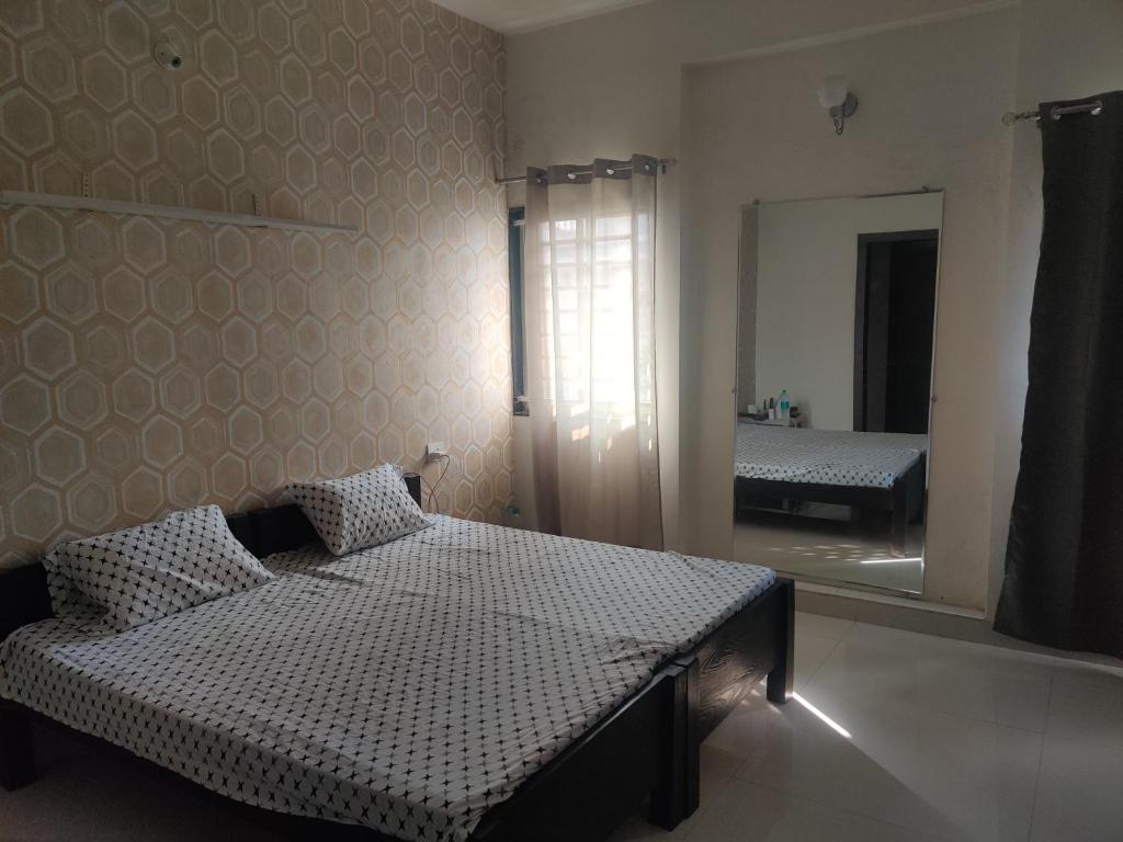 um quarto com uma cama e um espelho grande em Away From Home, Furnished Apartment em Bhopal