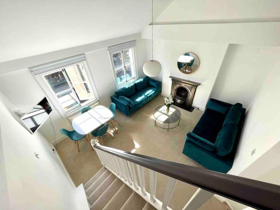 sala de estar con sofá verde y chimenea en Fab split level Kensington Apartment en Londres