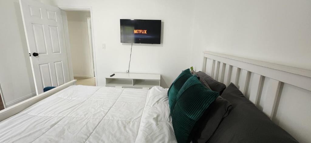 1 dormitorio con 1 cama y TV en la pared en Private Cozy & Spacious Room at a house with pool en Tamarac
