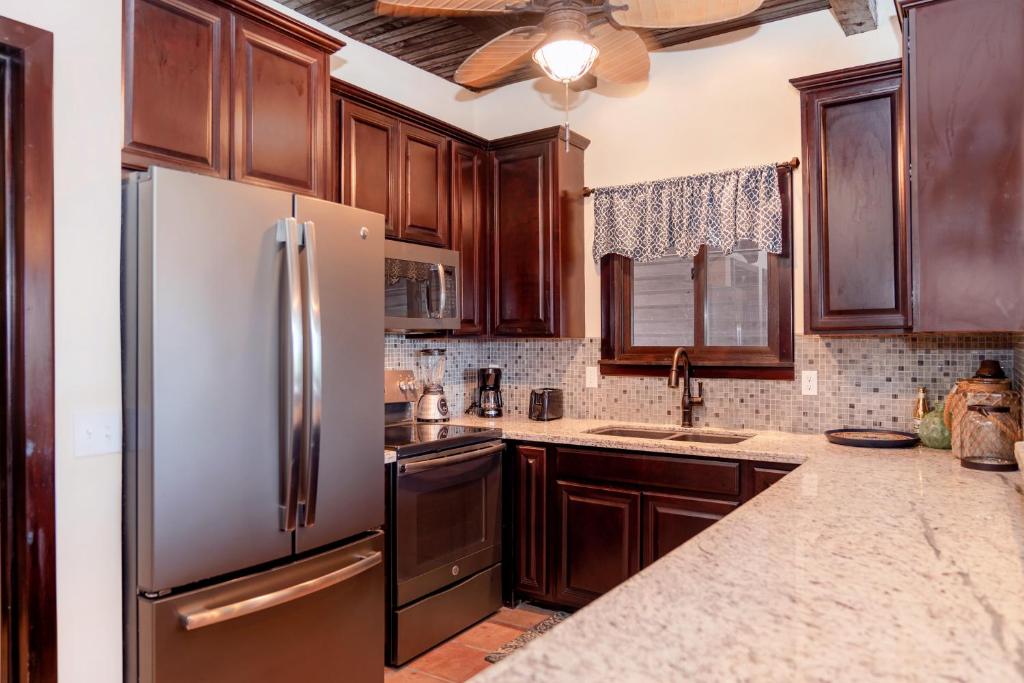 a kitchen with wooden cabinets and a stainless steel refrigerator at X'tan Ha- The Waterfront in San Pedro